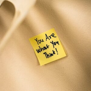 Yellow sticky note with motivational message on beige surface.